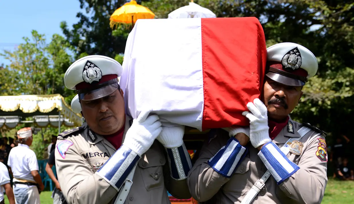 Petugas polisi menggotong peti mati berisi jenazah anggota Polsek Kuta, Aipda I Wayan Sudarsa, Bali, Minggu (21/8). Jenazah Sudarsa diselimuti bendera merah putih lalu diletakkan di sarana pembawa jasad dalam upacara ngaben. (SONNY Tumbelaka/AFP)