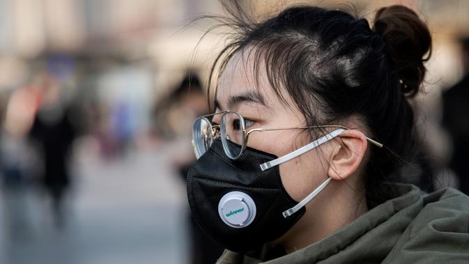 Seorang perempuan mengenakan masker penutup mulut berjalan menuju  stasiun kereta api Beijing untuk mudik Tahun Baru Imlek pada Selasa (21/1/2020). Wabah virus korona seperti SARS yang menyebar di China dan mencapai tiga negara Asia lainnya bisa menular dari manusia ke manusia. (NICOLAS ASFOURI/AFP)