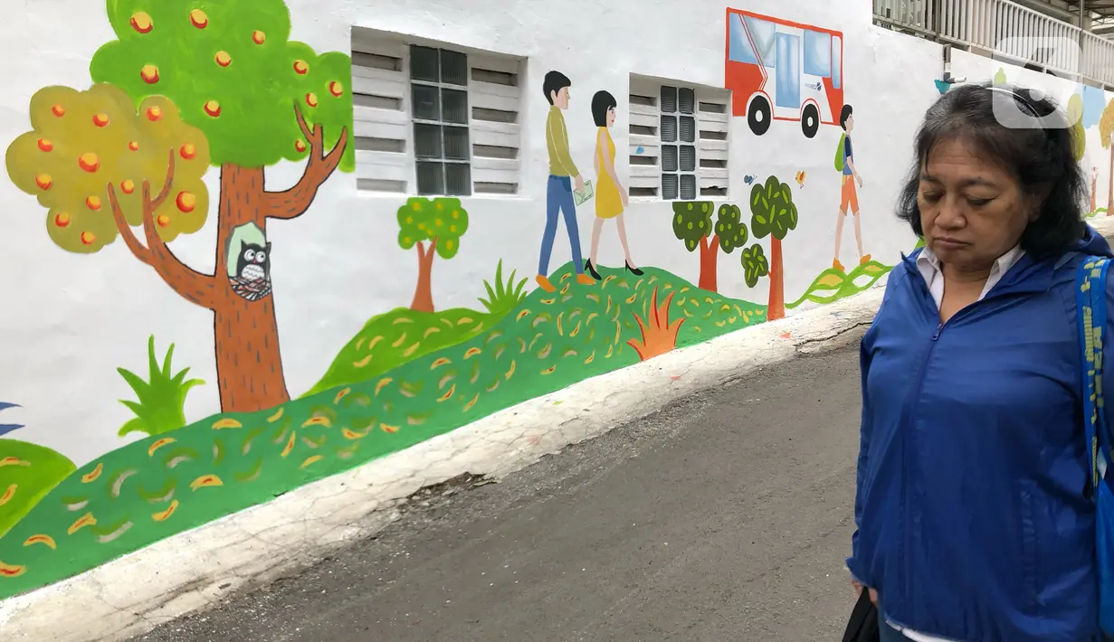 Warga melintas di depan mural dan akses khusus pejalan kaki di Jalan Darul Maarif, Jakarta Selatan, Rabu (11/3/2020). PT MRT Jakarta berkolaborasi dengan ITDP menata jalan-jalan sekitar stasiun untuk meningkatkan aksesibilitas warga sekitar. (Liputan6.com/Immanuel Antonius)