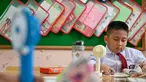 Seorang siswa sekolah dasar menggunakan kipas angin portabel untuk menyejukkan ruangan kelas saat cuaca panas di Banda Aceh pada 15 Mei 2023. (AFP/CHAIDEER MAHYUDDIN)