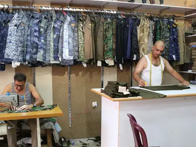 Penjahit Irak menyelesaikan pembuatan seragam militer di Baghdad (13/9). Perang yang berlangsung di Irak membuat para penjahit pakaian biasa kebanjiran orderan membuat seragam militer dan aksesorisnya. (AFP Photo/Sabah Arar)