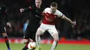 Duel antara Aaron Ramsey dan Benjamin Bourigeaud pada leg kedua,babak 16 besar Liga Europa yang berlangsung di Stadion Emirates, London, Jumat (15/3). Arsenal menang 3-0 atas Rennes. (AFP/Ian Kington)