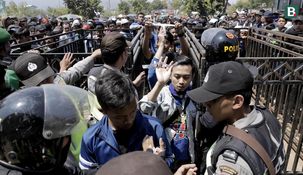 Petugas kepolisian memeriksa suporter di gerbang masuk Stadion GBLA, Jawa Barat, Minggu (23/9/2018). Pengamanan jelang laga Persib Bandung kontra Persija Jakarta diperketat. (Bola.com/M Iqbal Ichsan)