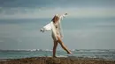 Terlihat riang, Pamela Bowie berpose di bebatuan pinggir pantai mengenakan two-pieces bikin yang seragam dengan scarf yang dipakainya sebagai bandana. Terlihat Pamela juga mengenakan oversized white shirt. Foto: Instagram.