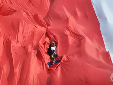 Sejumlah relawan membentang bendera Merah Putih raksasa saat mengikuti kirab budaya, Jakarta, Senin (20/10/2014) (Liputan6.com/Miftahul Hayat) 