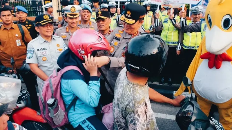 Kapolda Riau Irjen Iqbal memberikan dan memasangkan helm kepada warga dalam Operasi Keselamatan Lancang Kuning.
