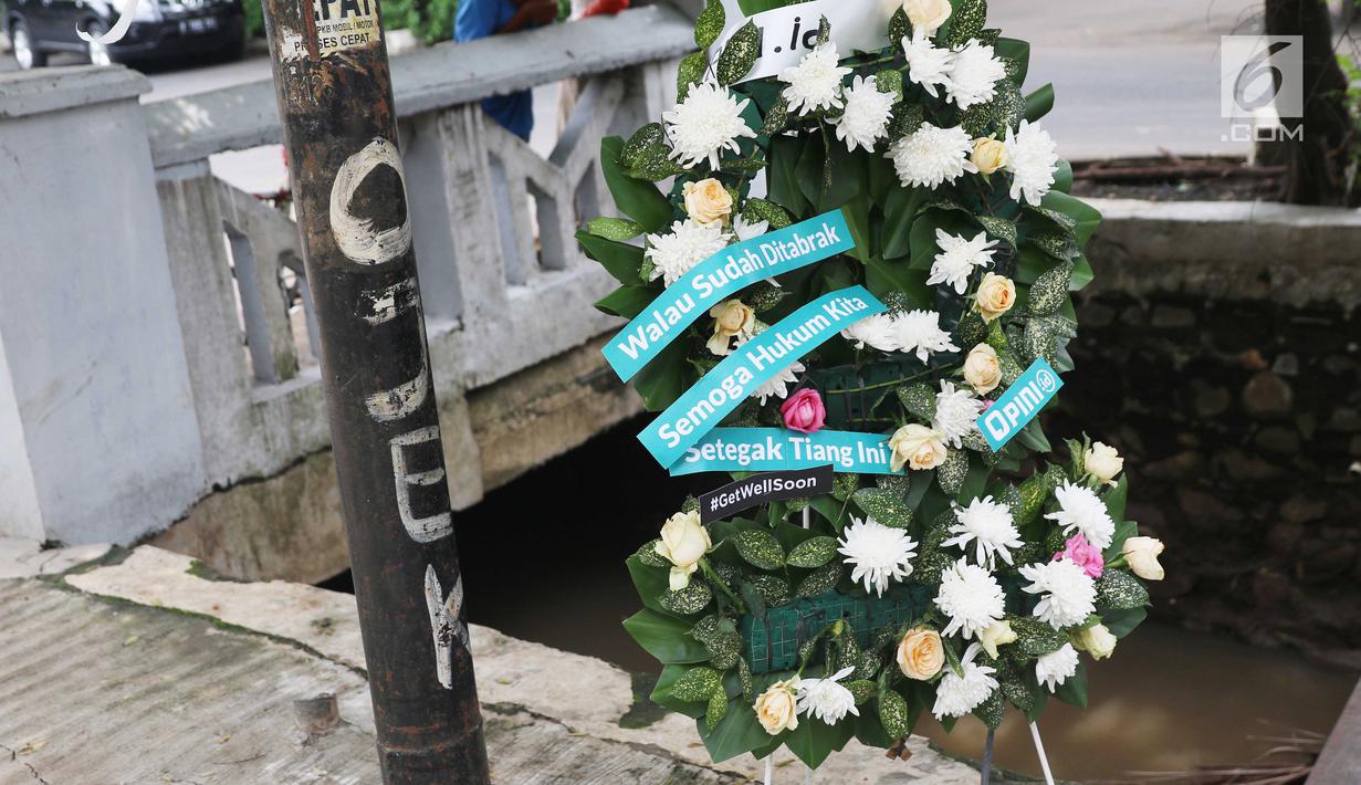 Sebuah karangan bunga berdiri dekat tiang lampu yang ditabrak mobil yang ditumpangi Ketua DPR Setya Novanto di Jalan Permata Berlian, Jakarta, Sabtu (18/11). Tiang lampu tersebut mendadak menjadi perhatian banyak masyarakat.  (Liputan6.com/Angga Yuniar)