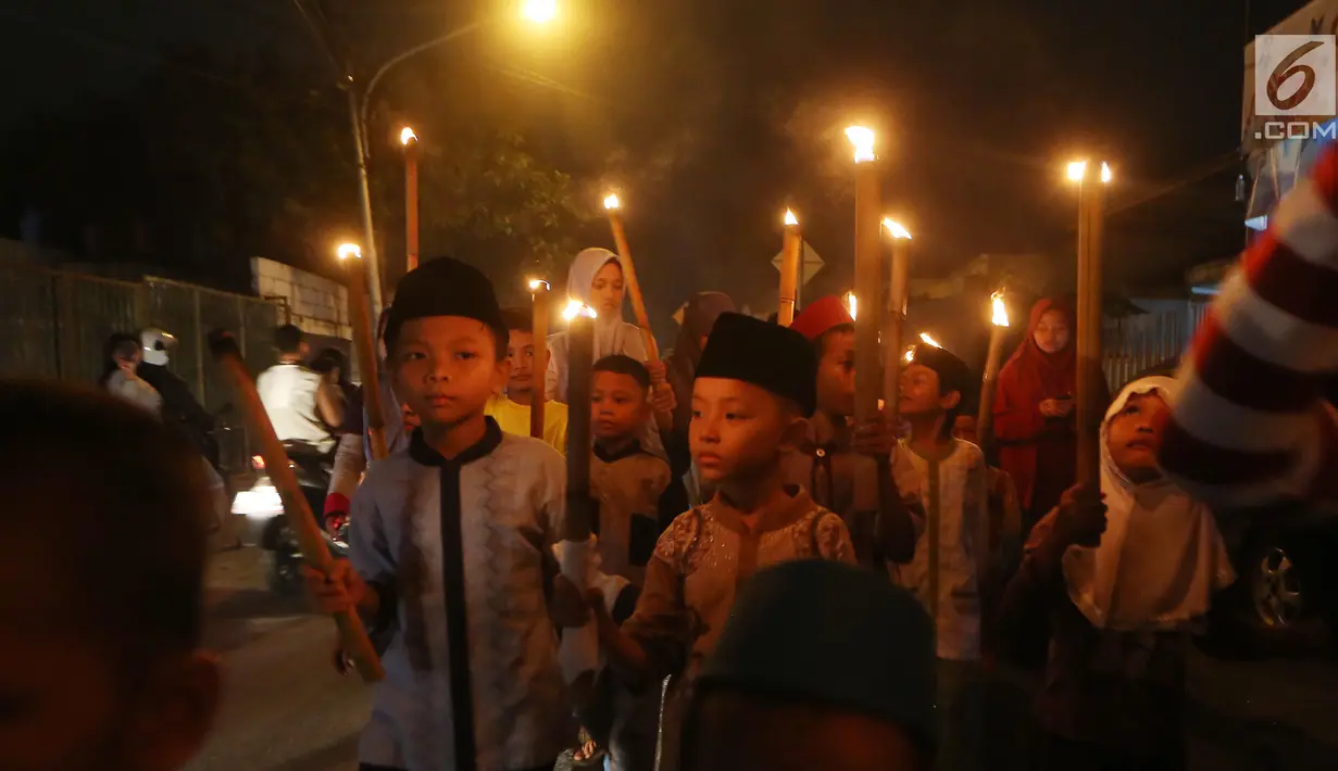 Sejumlah anak berpawai sambil membawa obor di Jalan Tengah, Batu Ampar, Jakarta Timur, Sabtu (24/6). Kegiatan tersebut dalam rangka menyambut Idul Fitri 1 Syawal 1438 Hijriyah. (Liputan6.com/Angga Yuniar)
