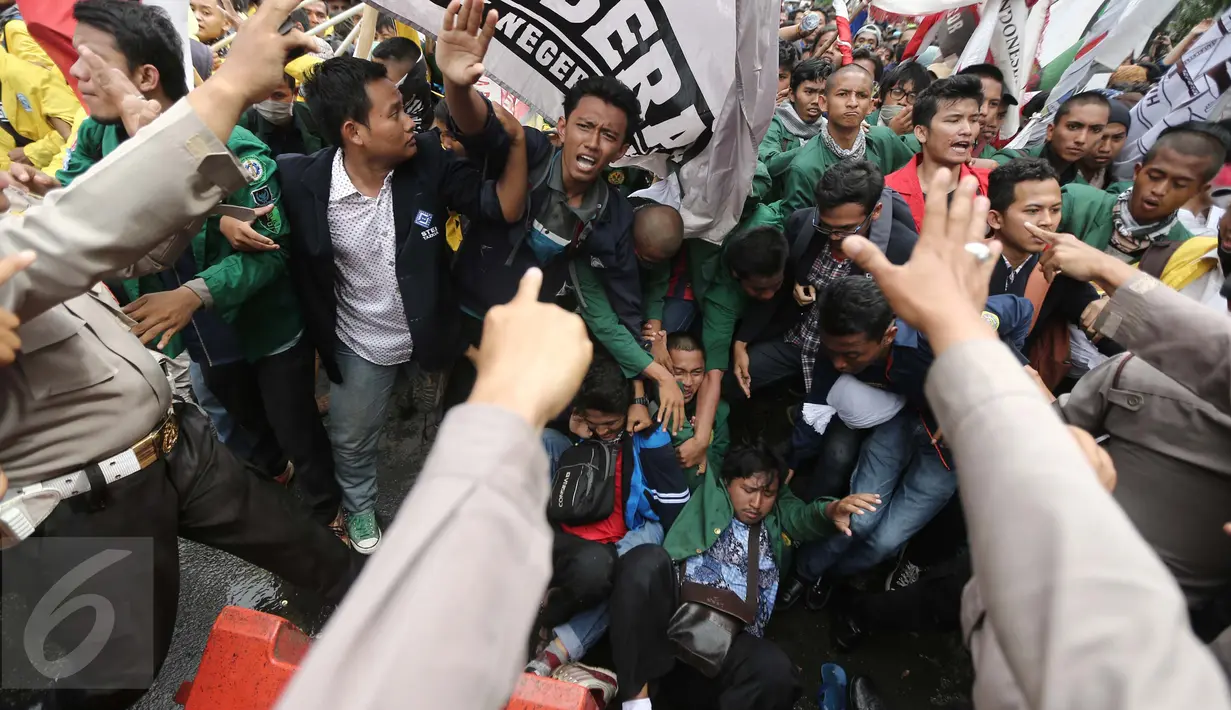 Sejumlah mahasiswa dari BEM Se-Jabodetabek terjatuh saat menggelar aksi unjuk rasa di depan Istana Negara, Kamis (12/1). Dalam aksinya mereka menuntut Presiden Jokowi-JK untuk membuat kebijakan yang pro terhadap rakyat. (Liputan6.com/Faizal Fanani)