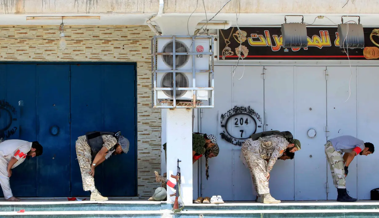 Sejumlah pasukan Libya melakukan salat sebelum mereka mempersiapkan diri untuk berperang melawan militan ISIS di Sirte, Libya (29/8). Dengan kondisi seadanya, mereka tak meninggalkan rukun Islam kedua itu. (REUTERS/Ismail Zitouni)