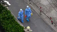 Petugas kesehatan yang mengenakan alat pelindung diri (APD) berjalan di jalan setelah meninggalkan lingkungan saat lockdown akibat virus corona COVID-19 di Distrik Jing'an, Shanghai, China, Sabtu (16/4/2022). (Hector RETAMAL/AFP)