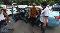 Para sopir taksi menurunkan penumpang sebuah taksi yang masih beroperasi saat aksi sweeping di Jalan Medan Merdeka Selatan, Jakarta, Senin (14/3). Ribuan sopir taksi dan bus kota menggelar unjuk rasa di Istana hari ini. (Liputan6.com/Immanuel Antonius)
