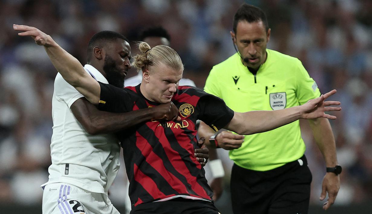 Pemain Manchester City, Erling Haaland (tengah) berebut bola dengan pemain Real Madrid, Antonio Rudiger pada laga leg pertama semifinal Liga Champions 2022/2023 di Santiago Bernabeu, Madrid, Rabu (10/05/2023) WIB. Laga berakhir dengan skor 1-1. (AFP/Oscar Del Pozo)