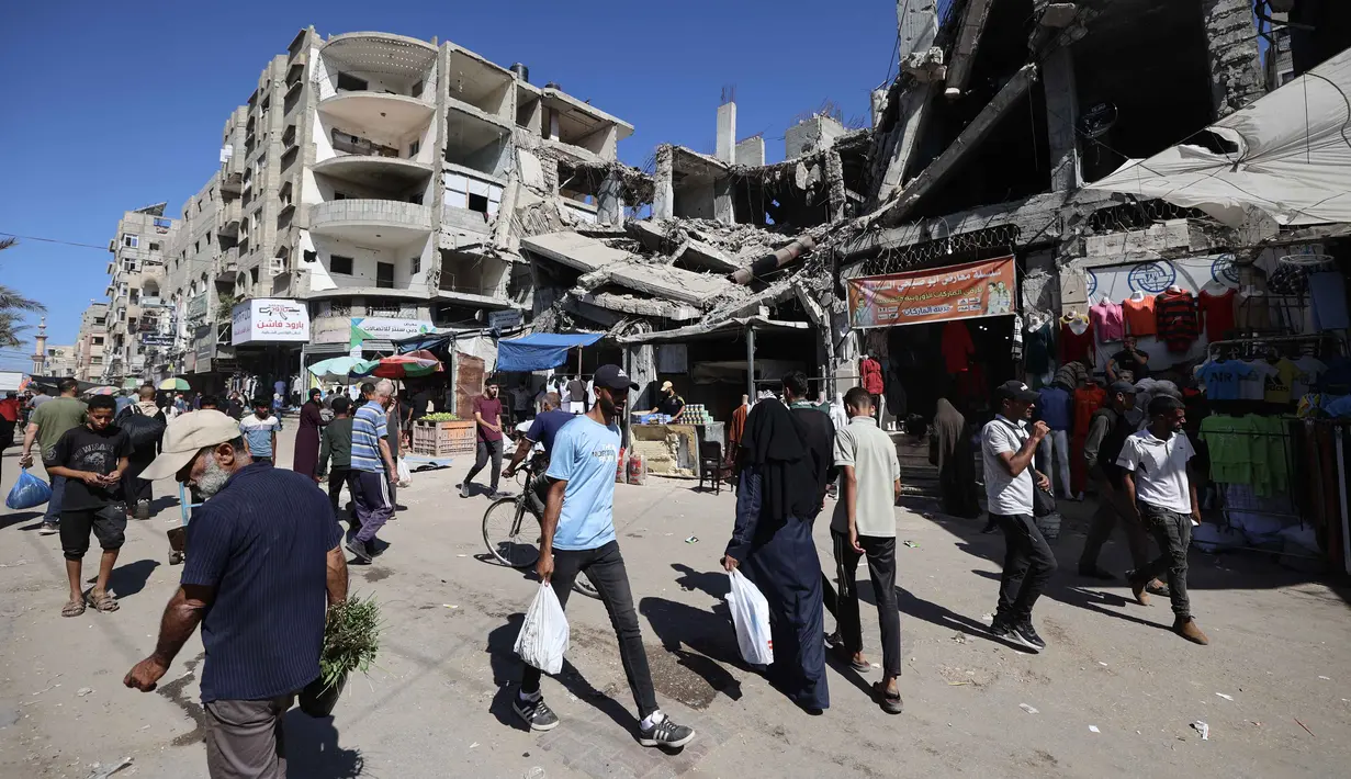 Di kamp pengungsi Nuseirat, pada 15 Oktober 2025, warga Palestina terpaksa berbelanja di pasar darurat yang dibangun di antara bangunan-bangunan yang hancur akibat serangan militer Israel. (Eyad BABA/AFP)