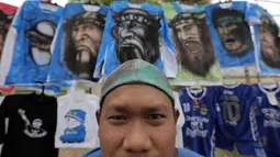Seorang pedagang atribut merapikan dagangan berupa Jersey dari airbrush di Stadion Si Jalak Harupat, Bandung, Sabtu (24/10/2015). (Bola.com / Nicklas Hanoatubun)