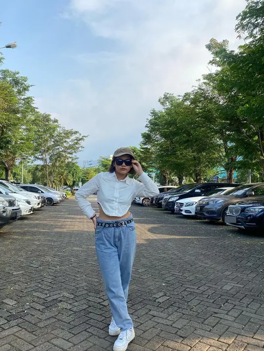 Tampil edgy dengan kemeja putih dengan potongan unik yang dipadukan celana jeans satu ini pun tak lepas dari perhatian netizen. Cinta Kuya juga turut menggunakan topi serta kacamata hitam dan iat pinggang untuk menambah detail penampilannya. (Liputan6.com/IG/@cintakuya)