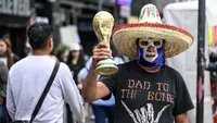 Seorang pedagang kaki lima yang mengenakan topeng gulat tradisional Meksiko memegang suvenir berbentuk trofi Piala Dunia FIFA di sebuah jalan di Kota Meksiko pada 8 Juni 2026. (Yuri CORTEZ/AFP)