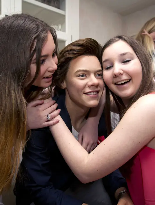 Patung lilin Harry Styles dipeluk oleh Suzanne dan Michelle yang memenangkan ‘home visit’ tokoh patung lilin dari Madame Tussaud di Nieuwegein, Belanda (1/6/2014). (Bintang/EPA)