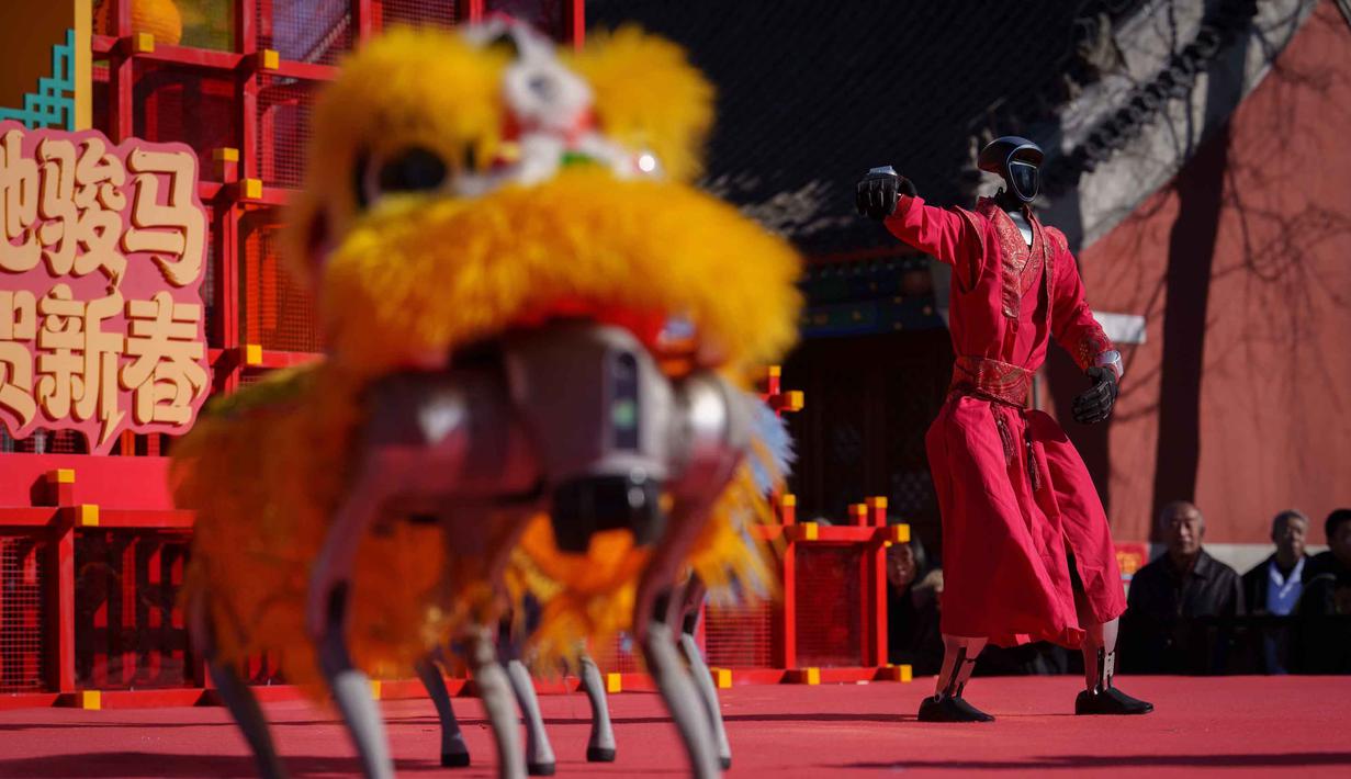 Robot-robot tersebut dirancang melakukan gerakan tarian yang lincah, dinamis, dan mengikuti irama musik tradisional. Tampak dalam foto, sebuah robot humanoid dengan pakaian merah meriah memberi isyarat di atas panggung sementara robot berkaki empat yang dilengkapi kepala singa tampil di latar depan selama hari kedua perayaan Tahun Baru Imlek 2577 Kongzili di sebuah pekan raya kuil di Beijing pada Rabu 18 Februari 2026. (AP Photo/Vincent Thian)
