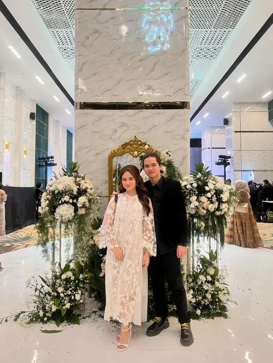 <p>Gaya manis pasangan Dul Jaelani dan Tissa Biani saat kondangan. Tissa Biani tampil cantik dengan dress lace berwarna putih, sedangkan Dul tampil serba hitam dengan kemeja lengan panjang berwarna hitam dan celana panjangnya. [Foto: Instagram/tissabiani]</p>