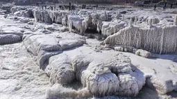 Para pengunjung sedang menikmati pemandangan musim dingin di tempat wisata Air Terjun Hukou di Provinsi Shaanxi, China pada 16 Desember 2020. Air terjun Hukou menyuguhkan pemandangan musim dingin nan spektakuler saat suhu udara terus turun dalam beberapa hari terakhir. (Xinhua/Tao Ming)