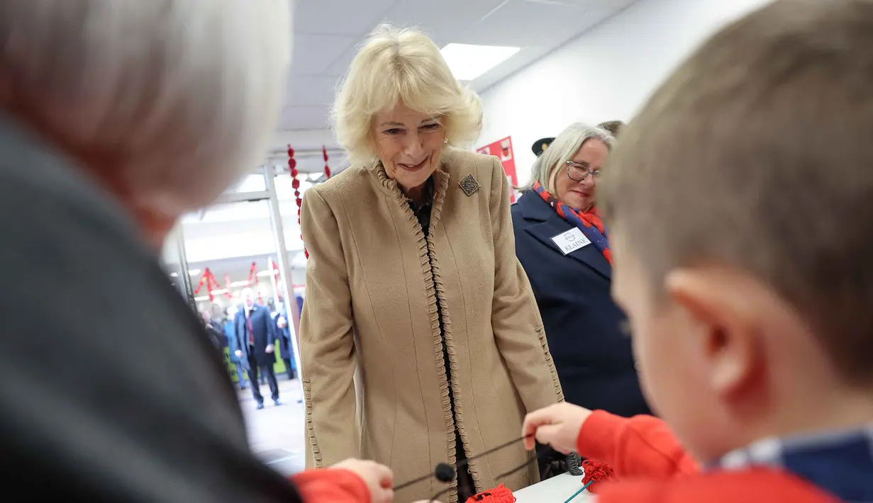 Ratu Inggris, Camilla, bereaksi saat mengunjungi lokakarya pembuatan bunga poppy di Pusat Perbelanjaan Martingate di Corsham, Inggris pada Selasa 28 Oktober 2025, sebagai bagian dari kunjungannya ke The Poppy Project. Ratu Inggris, Camilla, juga menyempatkan mengikuti lokakarya, di mana ia bertemu dengan para pembuat dan menyaksikan mereka mendemonstrasikan cara pembuatan masing-masing poppy. (Chris Jackson/POOL/AFP)