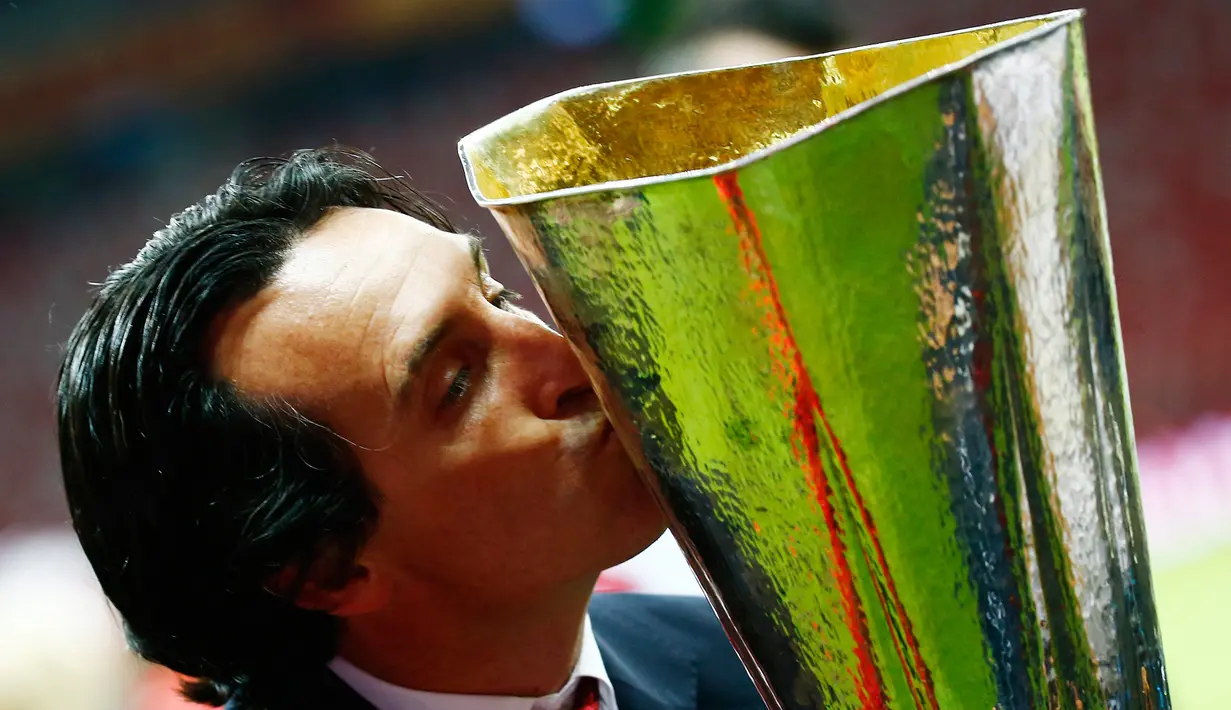 Pelatih Sevilla, Unai Emery mencium trofi di tengah perayaan gelar Liga Europa 2015 di Stadion Narodowy, Polandia, Kamis (28/5/2015). Sevilla memecahkan rekor meraih trofi Liga Europa terbanyak, yakni empat gelar. (Reuters/Kai Pfaffenbach)