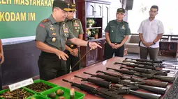 Panglima Kodam Iskandar Muda Mayjen TNI Teguh Arief Indratmoko memeriksa senjata bekas konflik di Banda Aceh, Aceh, Rabu (15/5/2019). Sembilan senjata laras panjang, tiga pistol, delapan granat, dan 455 butir amunisi tersebut diserahkan secara sukarela oleh warga. (CHAIDEER MAHYUDDIN/AFP)