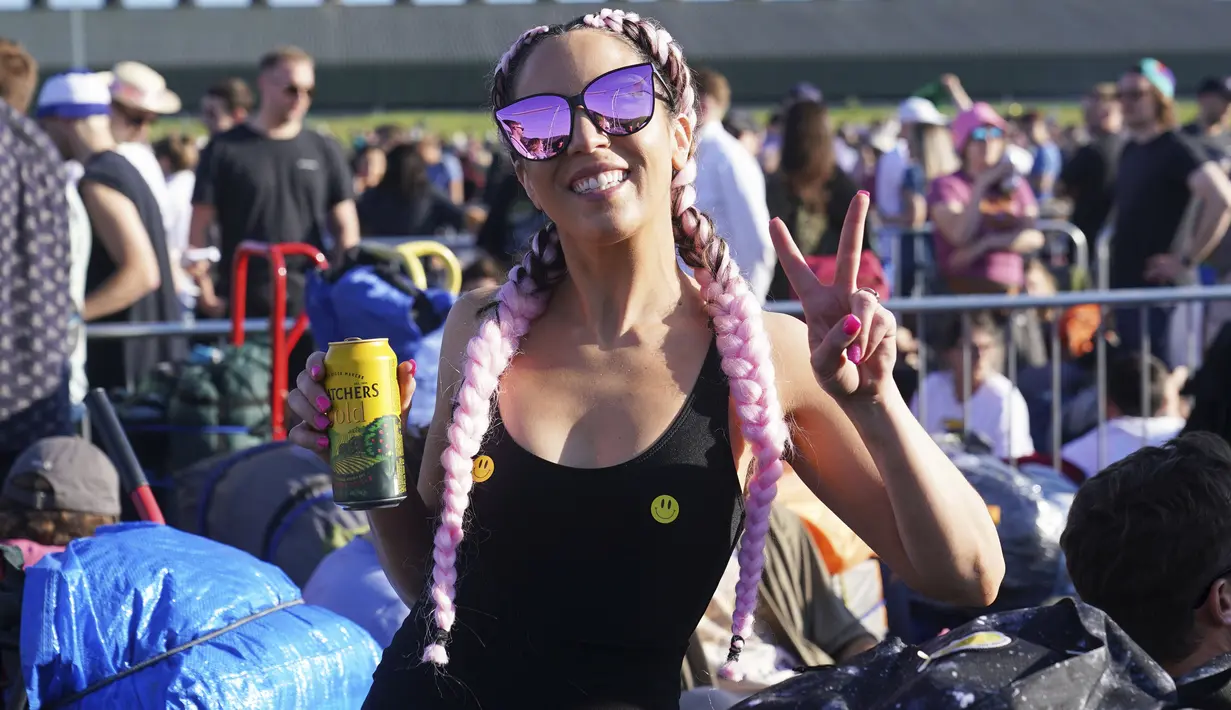 Seorang wanita berpose saat antre untuk masuk pada hari pertama Festival Glastonbury di Worthy Farm di Somerset, Inggris, Rabu (22/6/2022). Pandemi virus corona memaksa penyelenggara membatalkan acara, dan mereka yang pergi tahun ini menghadapi perjalanan yang sulit melawan tiga hari pemogokan kereta api besar di seluruh negeri. (Yui Mok/PA via AP)