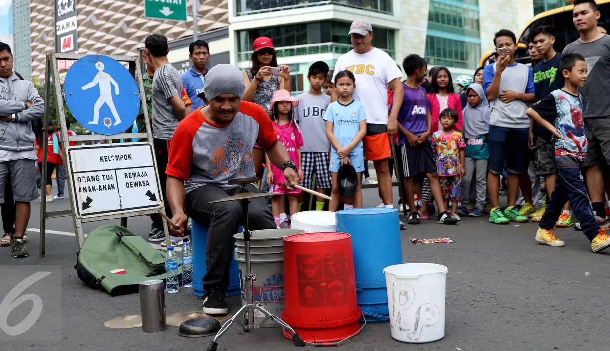 Pengamen perkusi memainkan alat musiknya yang terbuat dari ember bekas di kawasan Bundaran HI saat CFD, Jakarta, Minggu (10/9). Tidak hanya untuk olahraga, CFD juga menjadi sarana hiburan dan liburan murah di Jakarta. (Liputan6.com/Gempur M. Surya)