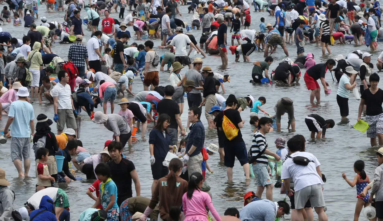 Sejumlah pengunjung berdesakan untuk berburu kerang di pantai kawasan Yokohama, dekat Tokyo, Senin (30/4). Ribuan orang membanjiri pantai selama Golden Week atau periode liburan di Jepang pada akhir April hingga awal Mei. (AP/Koji Sasahara)