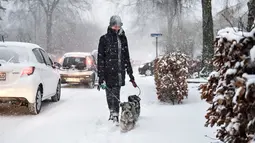 Wanita menuntun anjingnya melewati salju tebal di Aalborg, Denmark, Selasa (27/2). Cuaca dingin di Siberia yang dijuluki "The Beast from the East" membuat suhu di sebagian Eropa menurun. (AFP PHOTO/Scanpix DAN Ritzau SCANPIX/Henning Bagger/Denmark OUT)