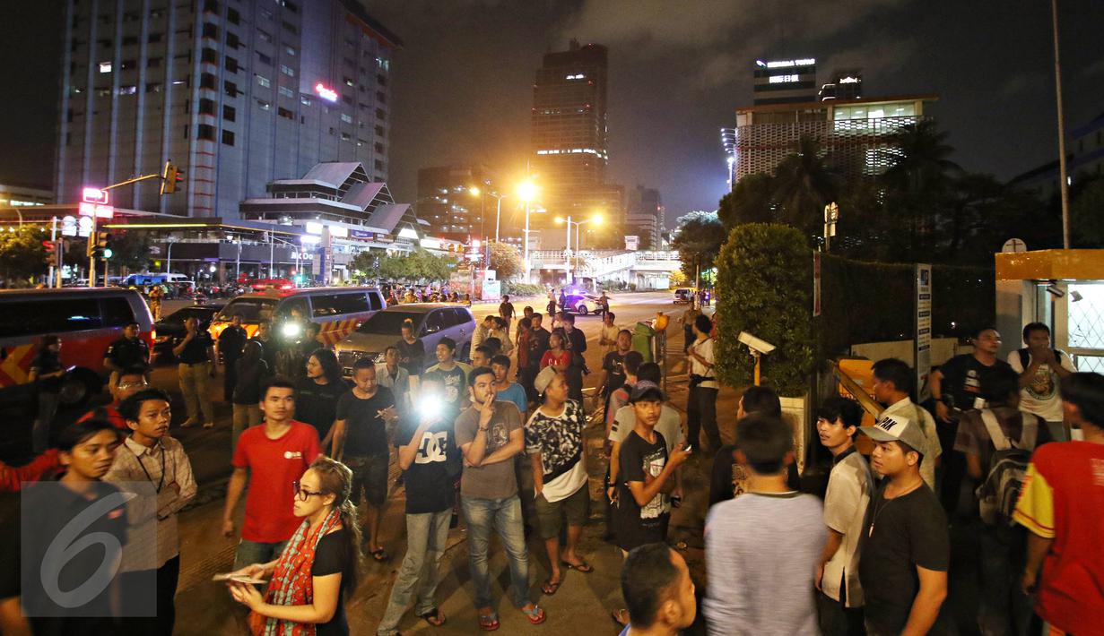 Warga tampak berkerumun di sekitar Gedung Jaya, Jalan MH Thamrin, Jakarta, setelah sebuah ledakan kembali terdengar, Kamis (14/1). Ledakan sempat membuat Jalan MH Thamrin kembali ditutup pada malam hari. (Liputan6.com/Immanuel Antonius)