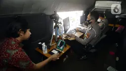 Petugas melayani warga yang mengurus SIM di Pelayanan SIM Keliling, Tangerang Selatan, Banten, Jumat (7/8/2020). Ditlantas Polda Metro Jaya memberi dispensasi bagi pemilik SIM yang masa berlakunya habis di masa pandemi COVID-19 bisa memperpanjang sampai akhir Agustus 2020. (merdeka.com/Dwi Narwoko)