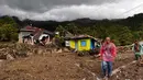 Warga berjalan melewati rumah-rumah yang rusak di sebuah desa yang terdampak banjir di Malalak, Sumatera Barat, Jumat 28 November 2025. Jelang akhir November 2025, bencana banjir bandang dan tanah longsor melanda sebagian besar wilayah pulau Sumatera. (AP Photo/Ade Yuandha)