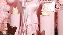 Pada look pertama, Syahrini mengenakan gaun panjang berwarna pink pastel dengan aksen ruffle di bagian bawahnya. Gaunnya tersebut dipadukan dengan hijab segi empat berwarna nude pink.  [@princessyahrini].