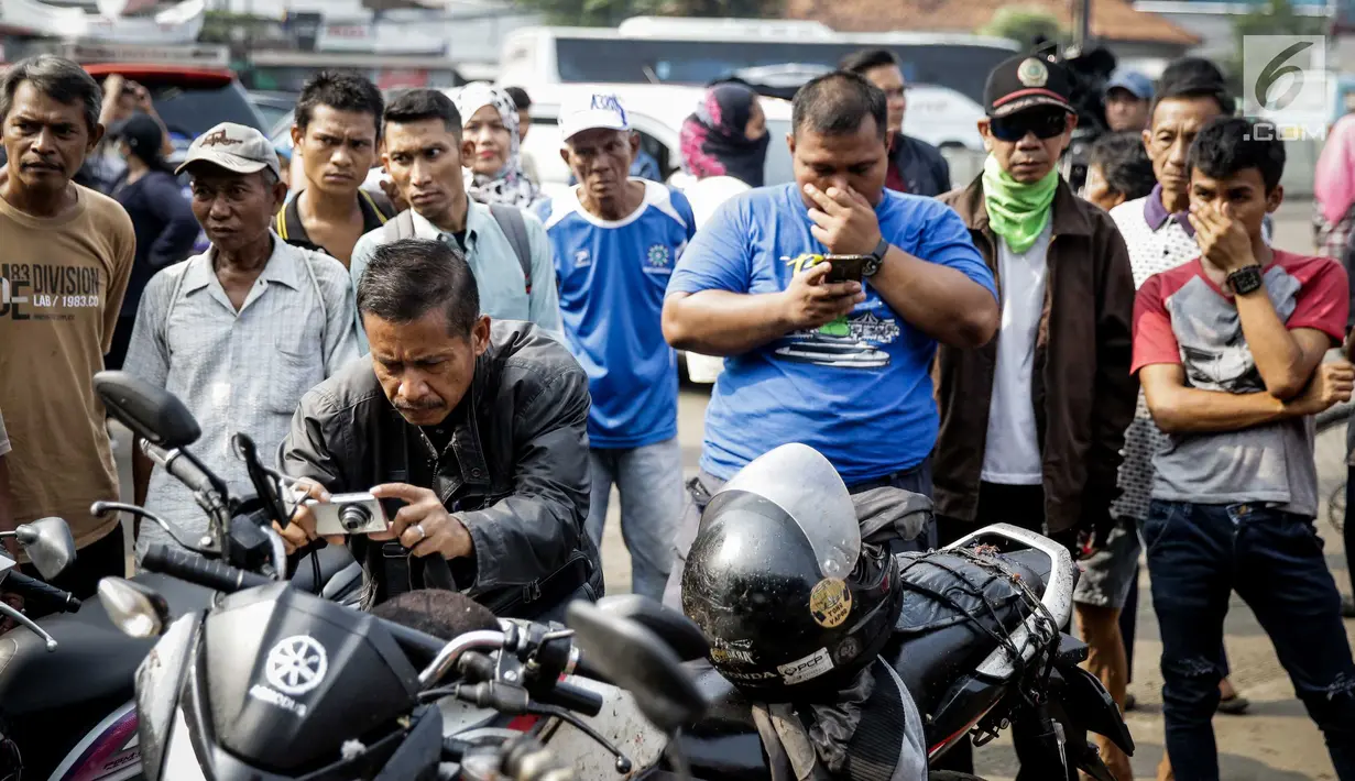 Warga menggunakan kamera untuk mengambil gambar di lokasi ledakan bom Kampung Melayu, Kamis (25/5). Lokasi terjadinya ledakan dipadati warga untuk berfoto dan melihat langsung peristiwa yang menewaskan tiga polisi tersebut. (Liputan6.com/Faizal Fanani)