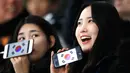 Dua wanita Fans Skating memperlihatkan ponsel mereka yang bergambar bendera Korea Selatan sebelum pertandingan balapan speed skater 1.500 meter pada Olimpiade Musim Dingin 2018 di Gangneung Oval, Korea Selatan, Selasa, (13/2). (AP Photo / Vadim Ghirda)