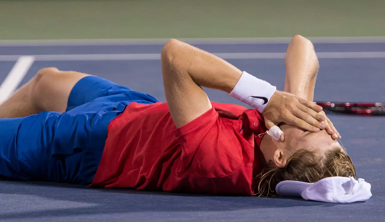 Petenis Kanada, Denis Shapovalov tergeletak di lapangan usai mengalahkan Rafael Nadal (Spanyol) pada turnamen Piala Rogers di Montreal, Kamis (10/8). Nadal disingkirkan petenis 18 tahun dengan skor 6-3, 4-6, 6-7. (Paul Chiasson/The Canadian Press via AP)