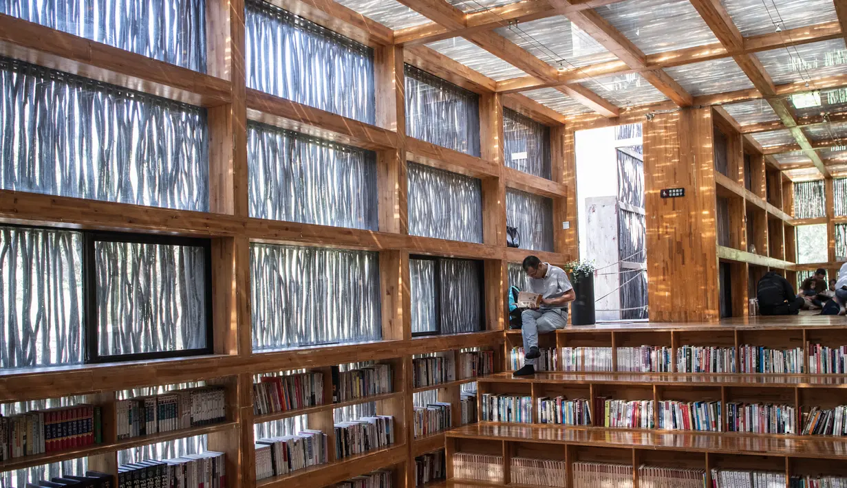 Foto pada 15 September 2018, seorang pria membaca buku di Perpustakaan Liyuan, pinggiran kota Beijing. Di dalam gedung, pengunjung dimanjakan dengan teduhnya sinar matahari yang masuk menembus celah-celah ranting. (FRED DUFOUR/AFP)
