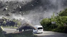 Batu-batu besar berjatuhan saat kendaraan melewati jalan selama gempa bumi di Bauko, Provinsi Mountain, Filipina, 27 Juli 2022. Gempa bumi kuat memicu tanah longsor dan merusak bangunan di Filipina. (AP Photo/Harley Palangchao)