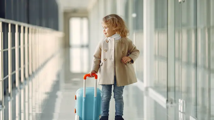 Seorang anak perempuan memegang koper mini di bandara (Foto Dok: Freepik/prostooleh)