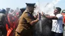 Sejumlah biksu dan aktivis bentrok dengan polisi saat aksi protes di kota pelabuhan selatan Hambantota, Sri Lanka (7/1). Akibat aksi ini, peresmian yang dihadiri oleh Perdana Menteri Ranil Wickeremesinghe, akhirnya tertunda. (AFP/Ishara S. Kodikara)