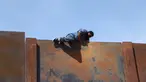 Seorang pemuda memanjat tembok besi perbatasan antara Meksiko dan Amerika Serikat di negara bagian Chihuahua, Meksiko (6/4). Mereka menyeberang secara ilegal ke Sunland Park dari Ciudad Juarez. (AFP/Herika Matinez)