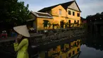 Gambar pada 14 September 2019 menunjukkan seorang turis mengenakan pakaian tradisional Vietnam ketika berpose di kota tua Hoi An. Kota Tua Hoi An merupakan destinasi wisata yang cukup populer di Vietnam, didukung oleh statusnya sebagai salah satu Unesco World Heritage Site. (Manan VATSYAYANA/AFP)