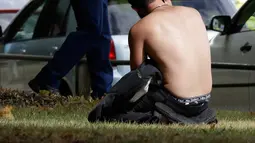 Seorang pria menggunakan telepon genggamnya dekat polisi bersenjata setelah insiden penembakan di Masjid Al Noor, Christchurch, Selandia Baru, Jumat (15/3). (AP Photo/Mark Baker)