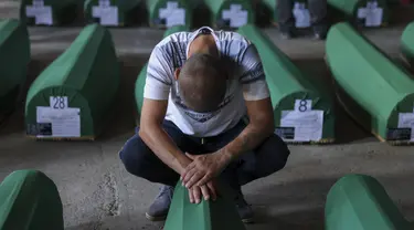 Seorang pria muslim berduka di samping peti mati kerabatnya, korban genosida Srebrenica 1995, di Potocari, Bosnia, Minggu (9/7/2023). Sebanyak 30 jenazah korban pembantaian Srebrenica yang baru diidentifikasi, satu-satunya genosida yang diakui di Eropa sejak Perang Dunia II, tiba di Pusat Peringatan di Potocari dimana mereka akan dimakamkan pada 11 Juli. (AP Photo/Armin Durgut)