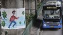 Bus transjakarta melintasi mural bertema protokol kesehatan Covid-19 yang menghiasi tiang pancang jalan tol di Jalan Ahmad Yani, Jakarta, Minggu (13/12/2020). (merdeka.com/Iqbal S. Nugroho)