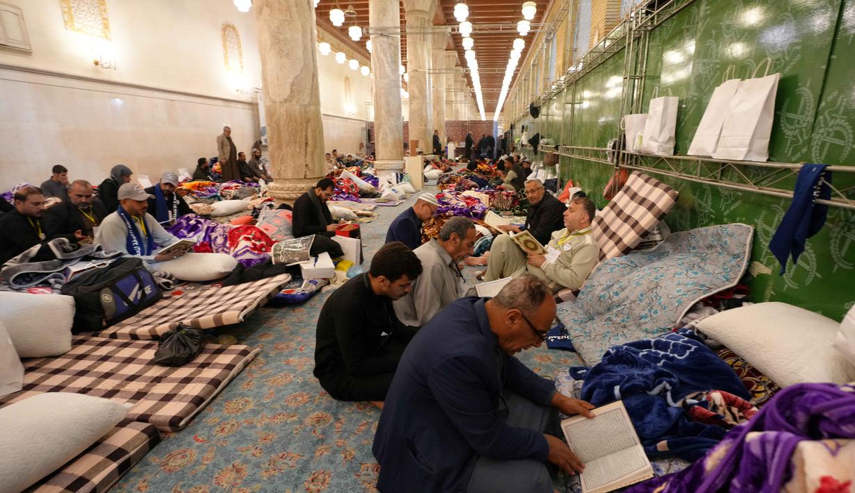 Selama 10 hari terakhir bulan suci Ramadan, membaca Al Quran menjadi aktivitas utama bagi mereka yang menjalankan Itikaf. Tampak dalam foto, umat Muslim Syiah, termasuk pengunjung dari Iran dan lainnya, membaca Al-Quran, saat melaksanakan Itikaf di Masjid Kufa, selatan Baghdad, Irak, pada 12 Maret 2026. (Qassem al-KAABI/AFP)