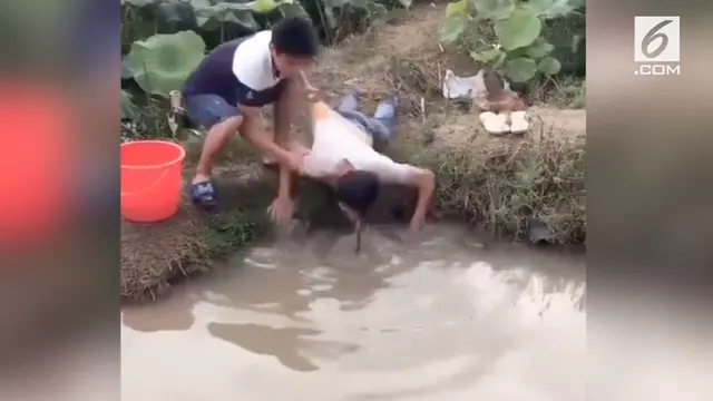 Seorang Pria memiliki cara unik menangkap ikan dengan memasukan kepala ke dalam kolam.
